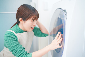 Fototapeta na wymiar ドラム式洗濯機が故障してショックを受ける女性