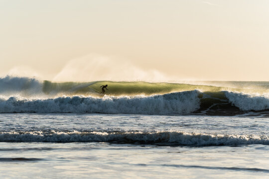 person inside the tube in the wave on the sea shore, high contrast