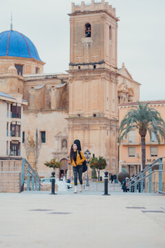Woman walking in the old town of a city with a guitar on her back