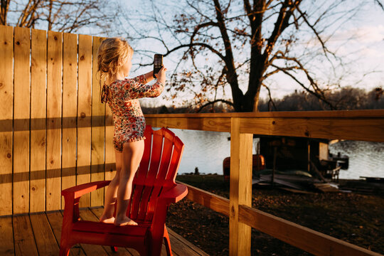 Child on vacation taking photos of lake from lake house
