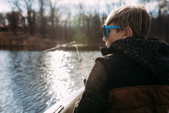 Boy fishing from kayak on lake during spring