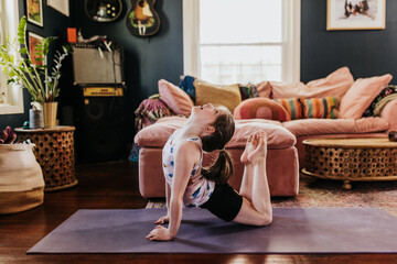 Young girl does yoga in her living room during the day