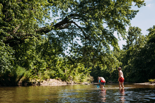 Boys catching crawdads in river on sunny summer day