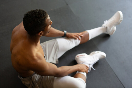 Fit Man Stretching in Gym with White Sneakers
