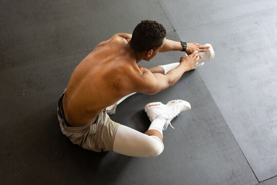 Fit Shirtless Man Stretching on Gym Floor