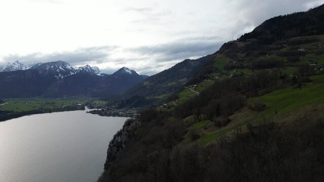Profile view of snow covered mountains and hills under cloudy sky in Walensee, Switzerland. Drone view.