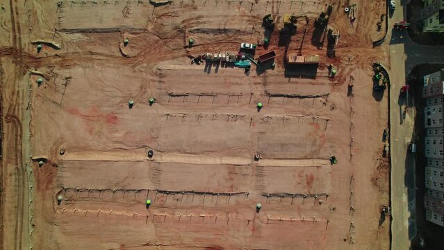 Top down aerial of huge construction site for residential home complex in South Atlanta, Georgia, USA. Telescopic Boom Lift, scissor lift, dirty parking lot.