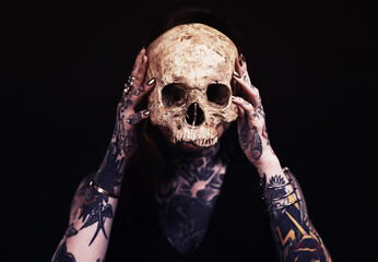 Skull, art and woman with tattoo in studio for dark magic, horror or scary aesthetic with object....