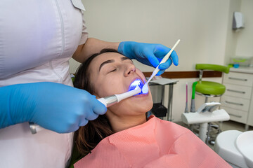  Woman patient receive procedure for teeth whitening bleaching with uv lamp