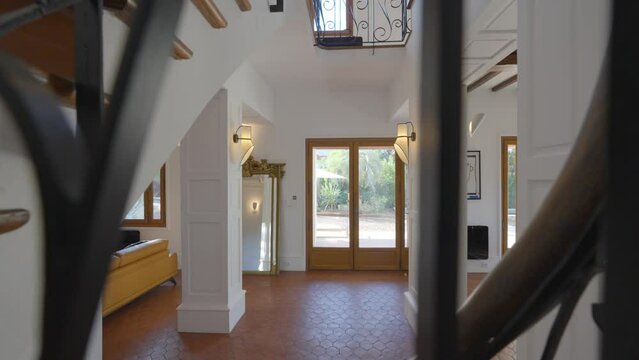 Slow dolly shot of the front door of a villa from a spiral staircase
