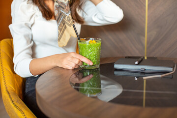 Woman hand holding glass of a green smoothie in the restaurant - 767686368