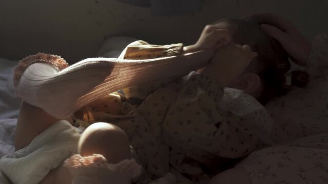 A little girl lies on the bed and takes off her stockings.