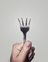 Bending, fork and hand with closeup, person and utensils with kitchen tool on a white studio...