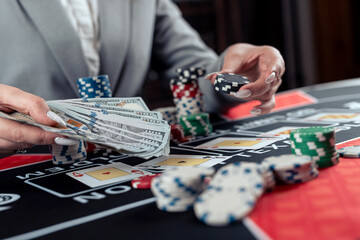 female player plays poker and takes chips to raise the bet - obrazy, fototapety, plakaty