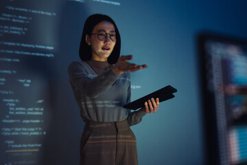 asian woman developer presentation about coding software data with devops team at night in office - 767692799
