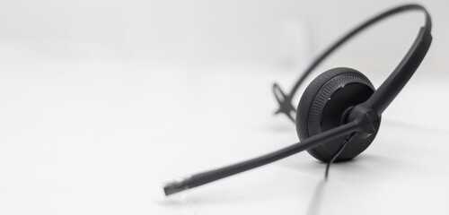 close up black headset on the white table background in 24/7 operation room to communicate with provider or response client for call center and hotline service concept - obrazy, fototapety, plakaty