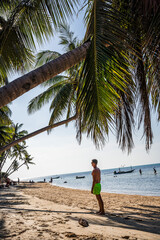 mężczyzna pod palmą na plaży - obrazy, fototapety, plakaty