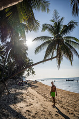 mężczyzna pod palmą na plaży - obrazy, fototapety, plakaty
