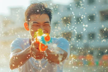 Foto op Plexiglas Happy traveler asian man wearing summer shirt holding colorful squirt water gun over blur city, Water festival holiday concept © grapestock