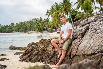 Mężczyzna na rajskiej plaży na kamieniu