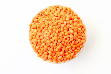 Uncooked red lentils in bowl on white background. Dry orange lentil grains. Top view