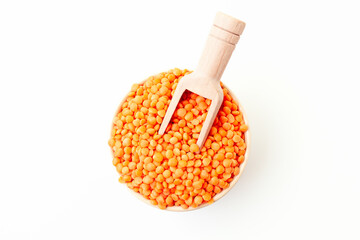 Dry red lentils in bowl with wooden scoop on white background. Top view