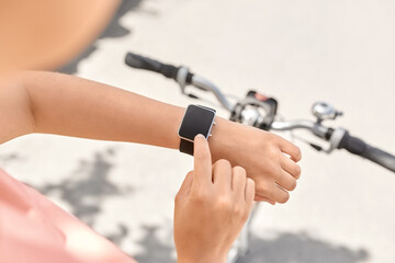 people, leisure and sport - close up of woman with smart watch riding bicycle on city street - 767710718