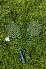 leisure games and sport equipment concept - close up of badminton rackets and shuttlecock on grass - 767711501
