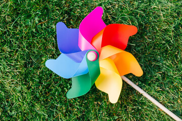 ecology, environment and sustainable energy concept - close up of multicolored pinwheel on green lawn or grass - 767711756