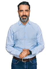 Middle aged man with beard wearing business shirt with hands together and crossed fingers smiling...