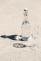 objects and drinks concept - bottle of water and glass on sunny floor - 767714541