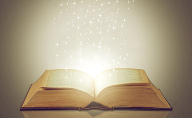 Magic, glowing pages and story with book, sparkle and literature on a grey studio background....