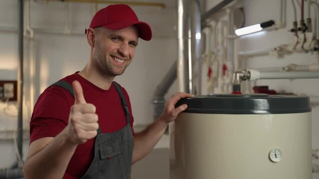 A professional technician, wearing a red cap and work overalls, is engaged in the maintenance of a large industrial boiler. The setting suggests a factory environment, and the meticulous attention to