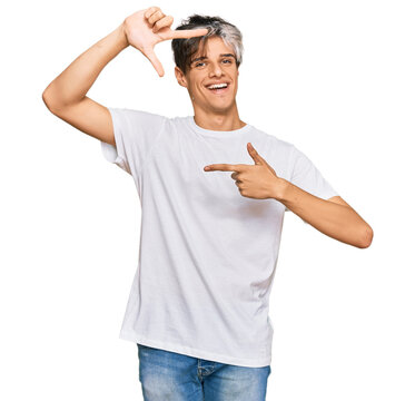 Young hispanic man wearing casual white tshirt smiling making frame with hands and fingers with happy face. creativity and photography concept.