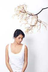 Woman, tree branch and fashion in studio with thinking, peace and growth in nature by white background. Girl, person or model with leaves, memory or relax with eyes closed for ecology, art or ideas
