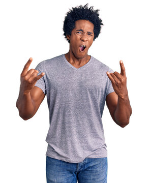 Handsome african american man with afro hair wearing casual clothes shouting with crazy expression doing rock symbol with hands up. music star. heavy concept.