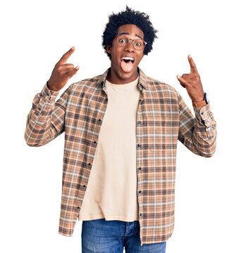Handsome african american man with afro hair wearing casual clothes and glasses shouting with crazy expression doing rock symbol with hands up. music star. heavy music concept.