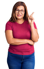 Middle age latin woman wearing casual clothes and glasses smiling happy pointing with hand and...