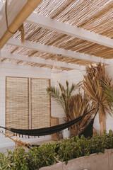 Cozy hammock, dried palm leaves. Aesthetic bohemian interior with natural straw and palm. Boho styled luxury resort hotel. Summer vacation holidays
