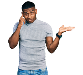 Young black man wearing casual t shirt confused and annoyed with open palm showing copy space and pointing finger to forehead. think about it.