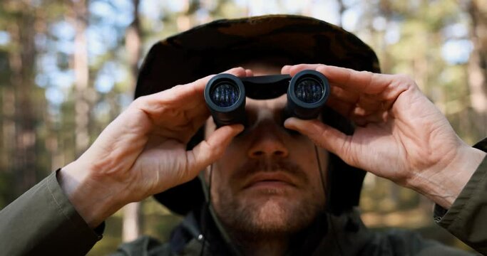 man looking through binoculars in forest. park monitoring, birdwaching