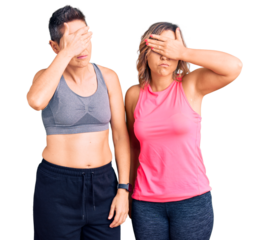Couple of women wearing sportswear covering eyes with hand, looking serious and sad. sightless, hiding and rejection concept