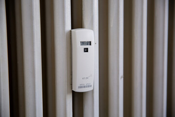 Close up of a wireless heat meter on white radiator. Heating of houses in the cold season - obrazy, fototapety, plakaty