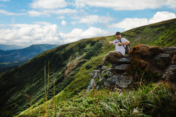Man on top of a mountain sitting on a rock
