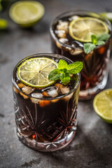 Tropical alcoholic cocktail Cuba Libre composed of white rum, cola, ice cubes, lime and mint - 767745930