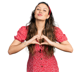 Young hispanic girl doing heart symbol with hands looking at the camera blowing a kiss being lovely and sexy. love expression.
