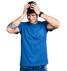 Young hispanic man wearing casual t shirt suffering from headache desperate and stressed because pain and migraine. hands on head.