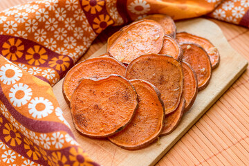 Sweet potato chips on a wooden chopping board.