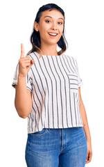 Young woman wearing casual clothes pointing finger up with successful idea. exited and happy. number one.