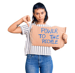 Young woman holding power to the people banner with angry face, negative sign showing dislike with...